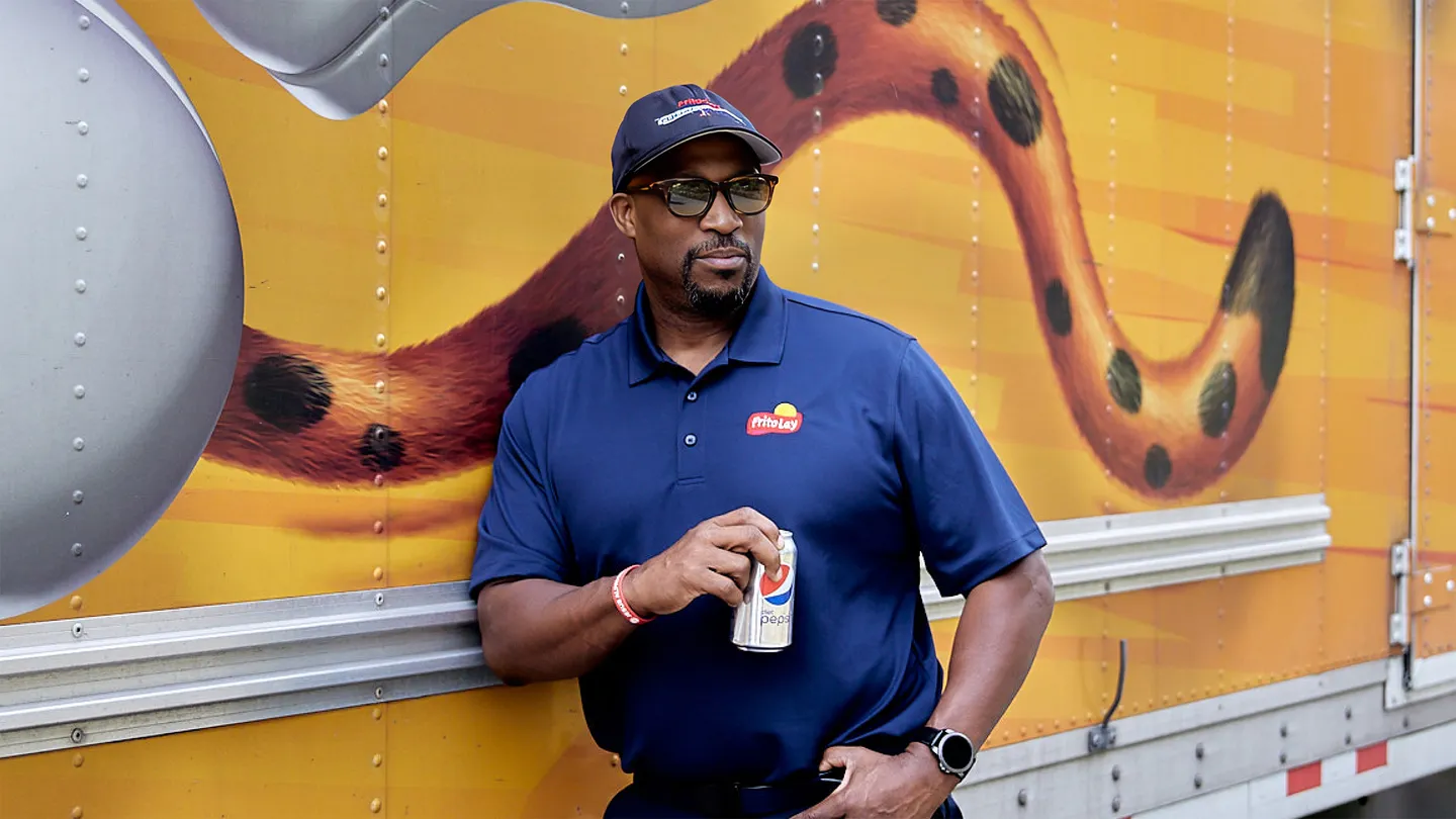 Man standing in front of semi truck drinking a Pepsi